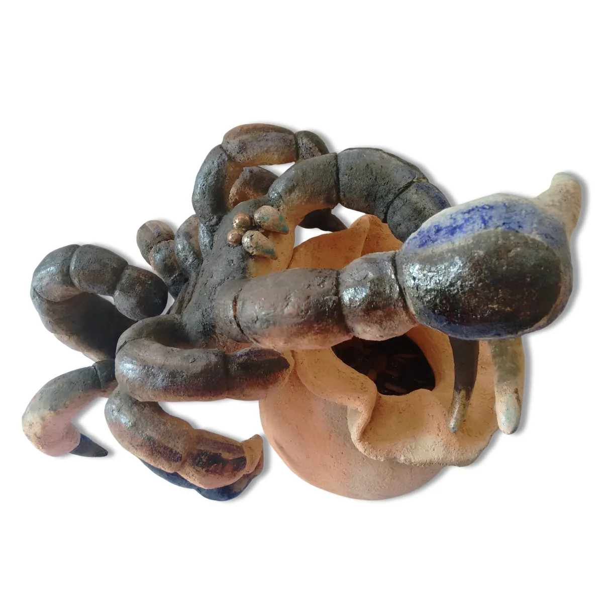 Escultura de cerámica con un alacrán protegiendo una bolsa de monedas como símbolo de los riesgos de la migración.