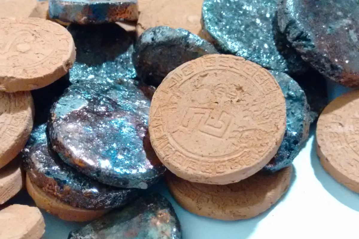 Monedas de cerámica con acabados naturales y metálicos.