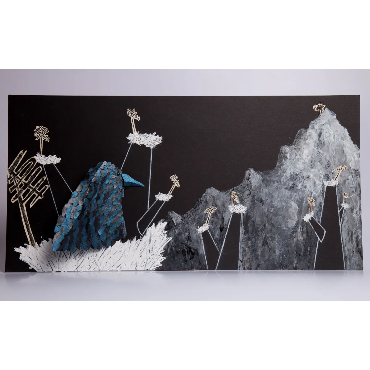 Personaje oscuro de papel frente a un paisaje montañoso pintado en blanco y negro.