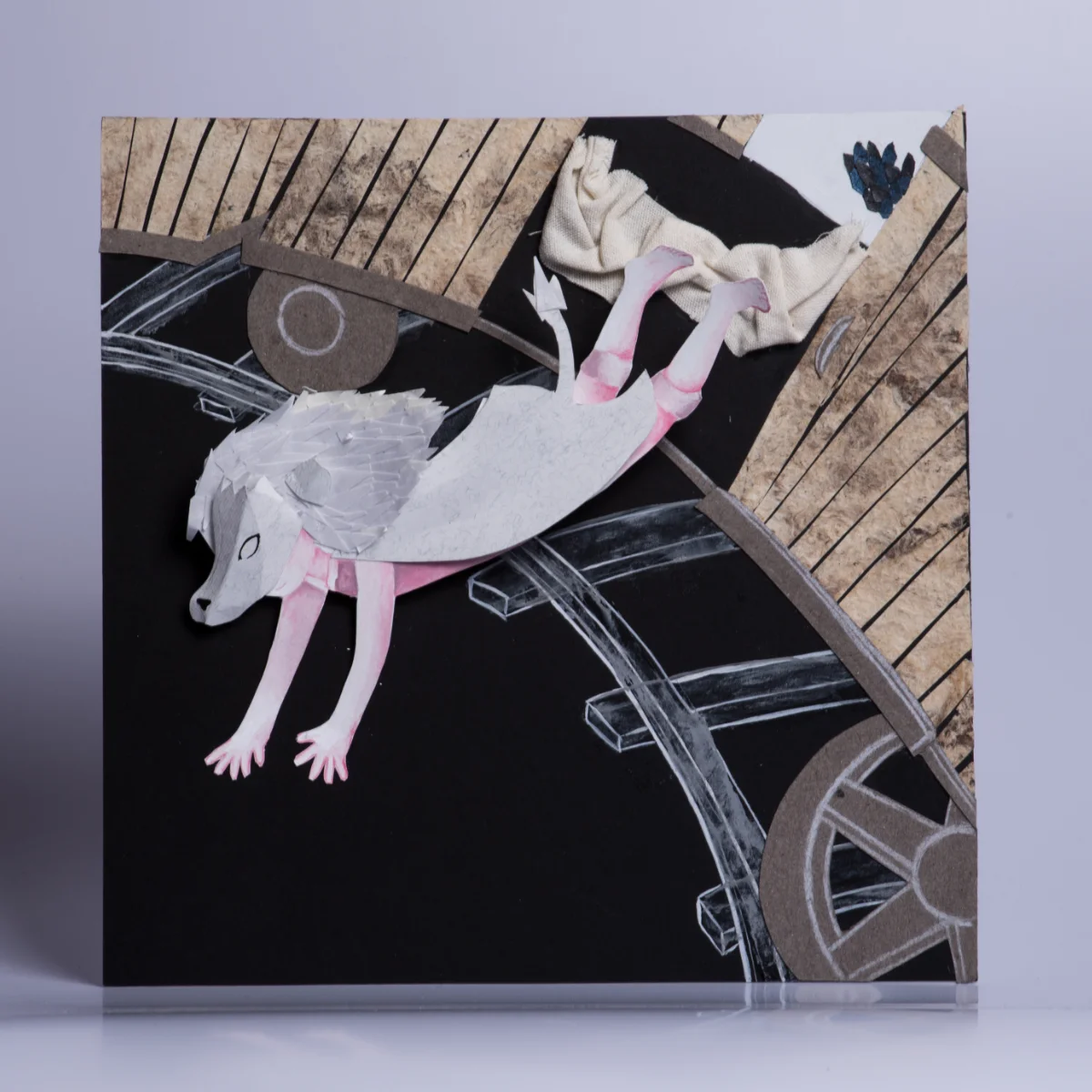Ilustración completa del personaje blanco cayendo sobre vías y ruedas construidas con papel.